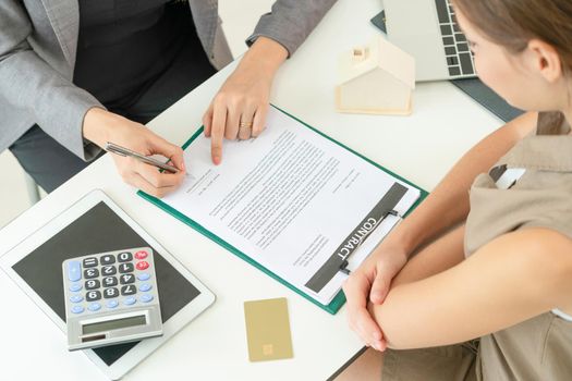 Client signs document regarding real estate activity next to lawyer or real estate agent sitting at office desk. Business concept of selling and buying house.