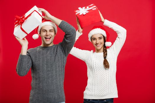 Christmas Concept - portrait young couple in Christmas sweater enjoy playing with gifts.