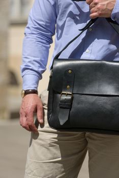 Man with a black leather briefcase with antique and retro look. Outdoors photo.