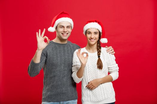 Christmas Concept - portrait lovely young couple showing ok gesture with finger to camera.