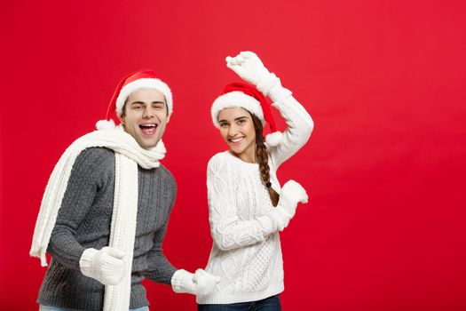 Christmas concept - Happy young couple in sweatesr celebrating christmas with playing and dancing.
