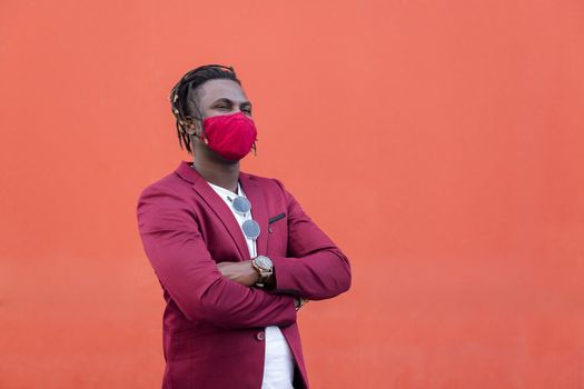 stylish african man with protective mask to match his suit on a red background, concept of elegance and fashionable lifestyle, copy space for text