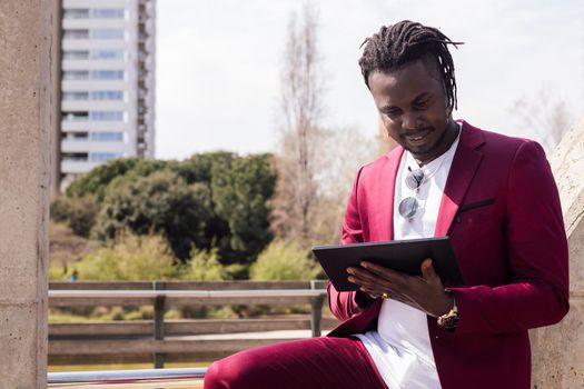 african businessman typing on a tablet outdoors in the city, technology and remote work concept, copy space for text