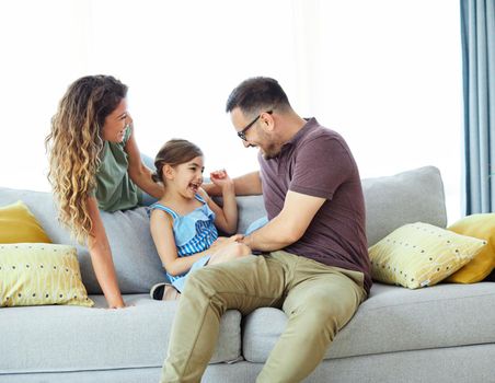 Family having fun playing on sofa at home