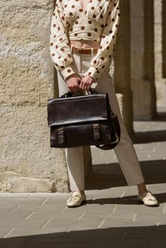 Woman with a brown leather briefcase with antique and retro look. Outdoors photo.