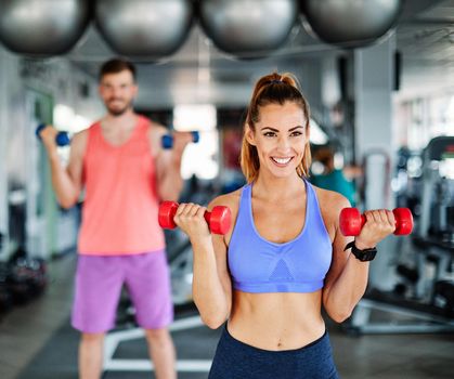 Happy healthy fit people at the gym exercising