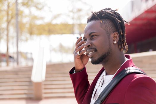 elegant black businessman listens to a voice message on his smart phone while walking through the city, copy space for text, concept of technology and communication