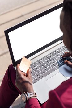 vertical photo of an unrecognizable man paying with his credit card for the online purchase made with his laptop computer, concept of technology and online shopping