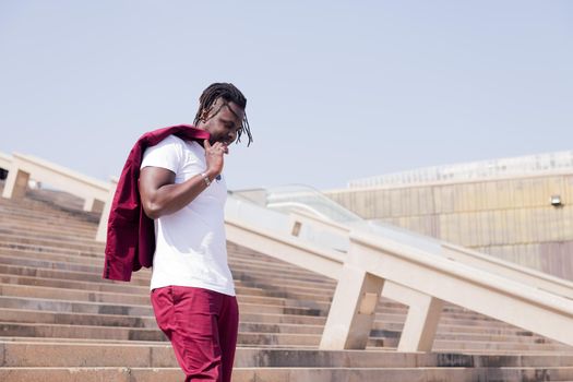 stylish black man walking down a city staircase with his blazer over his shoulder, urban lifestyle concept, copy space for text