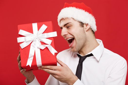 Christmas Concept - portrait close-up Santa christmas businessman over red background holding red gift.