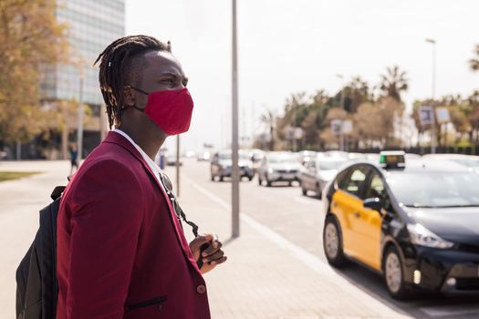 black businessman walking around the city with a red mask to match his suit, concept of elegance and fashionable lifestyle, copy space for text