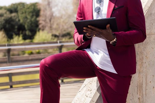 unrecognizable black businessman using a tablet outdoors in the city, technology and remote work concept, copy space for text