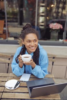 Beautiful young mixed-race stylish woman with piercing holding coffee, smiling. Top view. Vertical.