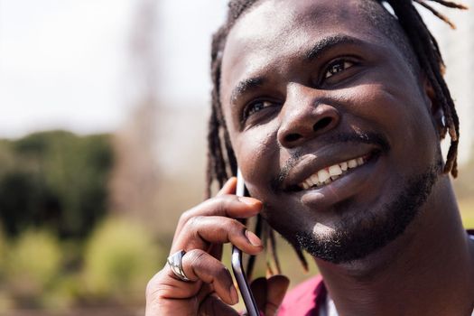 smiling black man talking on a smart phone outdoors, concept of technology and communication