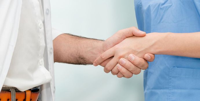Doctor in hospital handshake with another doctor. Healthcare people teamwork and medical service concept.