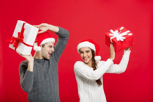 Christmas Concept - portrait young couple in Christmas sweater enjoy playing with gifts.