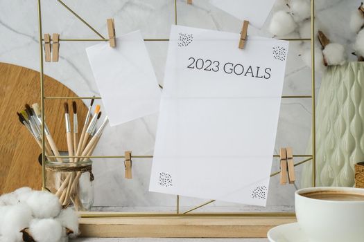 2023 GOALS Cards and posters mock ups on grid board. Copy space. Home office desktop. Freelance bloggers workplace. Brushes and palette tools Creative