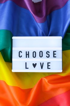 Rainbow flag with lightbox and text CHOOSE LOVE. Rainbow lgbtq flag made from silk material. Symbol of LGBTQ pride month. Equal rights. Peace and freedom. Support LGBTQ community