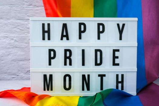 Rainbow flag with lightbox and text HAPPY PRIDE MONTH. Rainbow lgbtq flag made from silk material. Symbol of LGBTQ pride month. Equal rights. Peace and freedom. Support LGBTQ community