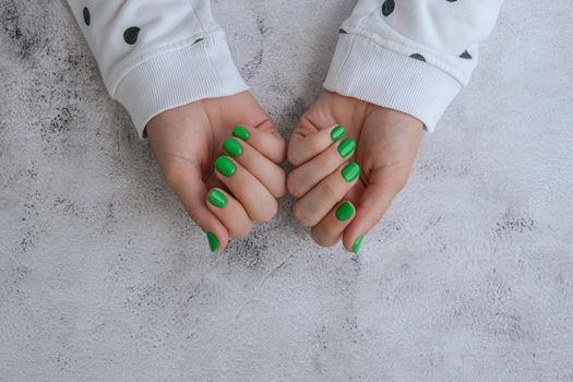 Manicured female hands with stylish green nails. Trendy modern design manicure. Gel nails. Skin care. Beauty treatment. Nail care. Wellness. Trendy colors.