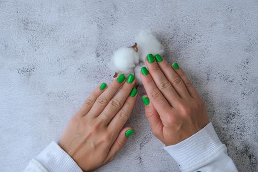 Manicured female hands with stylish green nails. Trendy modern design manicure. Gel nails. Skin care. Beauty treatment. Nail care. Wellness. Trendy colors.