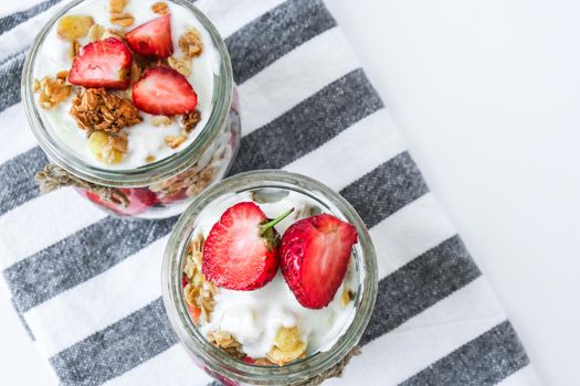 Healthy breakfast. Oatmeal Granola with greek yogurt and nuts strawberry muesli in jars on light background. Vegan, vegetarian and weight loss diet concept. Detox menu. Healthy eating food