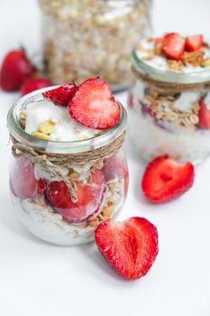 Healthy breakfast. Oatmeal Granola with greek yogurt and nuts strawberry muesli in jars on light background. Vegan, vegetarian and weight loss diet concept. Detox menu. Healthy eating food