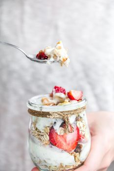 Female hands woman eating Healthy breakfast. Oatmeal Granola with greek yogurt and nuts strawberry muesli in jars on light background. Fitness. Weight loss diet concept. Detox menu. Healthy eating food