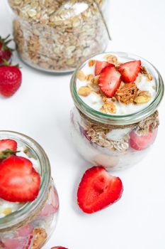 Healthy breakfast. Oatmeal Granola with greek yogurt and nuts strawberry muesli in jars on light background. Vegan, vegetarian and weight loss diet concept. Detox menu. Healthy eating food