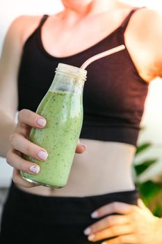 Young millenial blond woman drinking vegan smoothie drink detox. Woman doing yoga exercises at home. Clean eating, weight loss, healthy dieting food concept. Stay healthy. Wellness