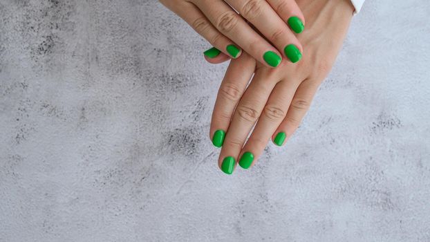 Manicured female hands with stylish green nails. Trendy modern design manicure. Gel nails. Skin care. Beauty treatment. Nail care. Wellness. Trendy colors.