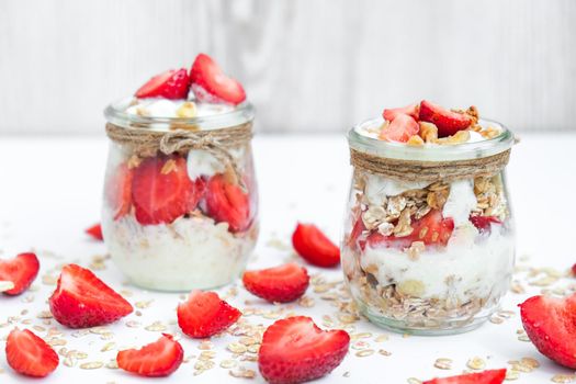 Healthy breakfast. Oatmeal Granola with greek yogurt and nuts strawberry muesli in jars on light background. Vegan, vegetarian and weight loss diet concept. Detox menu. Healthy eating food