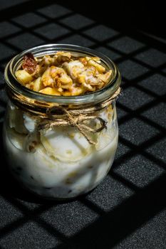 Healthy breakfast. Oatmeal Granola with greek yogurt and nuts banana muesli in jars on dark background. Trendy shadows Vegan, vegetarian and weight loss diet concept. Detox menu. Healthy eating food