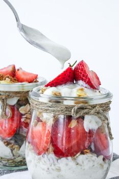 Healthy breakfast. Oatmeal Granola with greek yogurt and nuts strawberry muesli in jars on light background. Vegan, vegetarian and weight loss diet concept. Detox menu. Healthy eating food