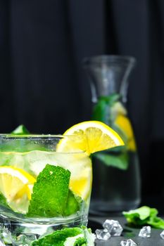 Mojito refreshing cocktail, alcohol drink. Lemonade with lemon and mint leaves on dark background. Ice cubes. Summer refreshing detox drinks. Clean eating, healthy lifestyle concept, Diet. Nutrition