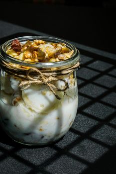 Healthy breakfast. Oatmeal Granola with greek yogurt and nuts banana muesli in jars on dark background. Trendy shadows Vegan, vegetarian and weight loss diet concept. Detox menu. Healthy eating food