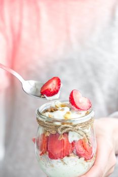 Female hands woman eating Healthy breakfast. Oatmeal Granola with greek yogurt and nuts strawberry muesli in jars on light background. Fitness. Weight loss diet concept. Detox menu. Healthy eating food