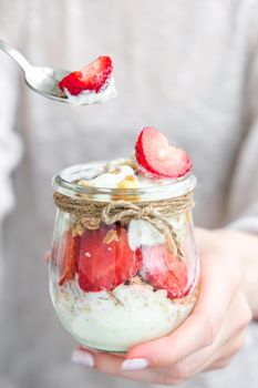 Female hands woman eating Healthy breakfast. Oatmeal Granola with greek yogurt and nuts strawberry muesli in jars on light background. Fitness. Weight loss diet concept. Detox menu. Healthy eating food