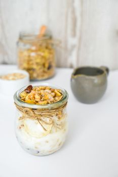 Healthy breakfast. Oatmeal Granola with greek yogurt and nuts banana muesli in jars on light background. Vegan, vegetarian and weight loss diet concept. Detox menu. Healthy eating food