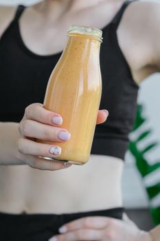 Young millenial blond woman drinking vegan smoothie drink detox. Woman doing yoga exercises at home. Clean eating, weight loss, healthy dieting food concept. Stay healthy. Wellness