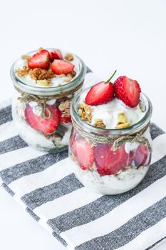 Healthy breakfast. Oatmeal Granola with greek yogurt and nuts strawberry muesli in jars on light background. Vegan, vegetarian and weight loss diet concept. Detox menu. Healthy eating food