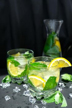 Mojito refreshing cocktail, alcohol drink. Lemonade with lemon and mint leaves on dark background. Ice cubes. Summer refreshing detox drinks. Clean eating, healthy lifestyle concept, Diet. Nutrition