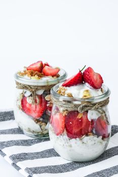 Healthy breakfast. Oatmeal Granola with greek yogurt and nuts strawberry muesli in jars on light background. Vegan, vegetarian and weight loss diet concept. Detox menu. Healthy eating food