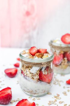 Healthy breakfast. Oatmeal Granola with greek yogurt and nuts strawberry muesli in jars on light background. Vegan, vegetarian and weight loss diet concept. Detox menu. Healthy eating food