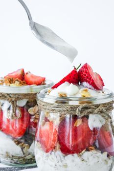 Healthy breakfast. Oatmeal Granola with greek yogurt and nuts strawberry muesli in jars on light background. Vegan, vegetarian and weight loss diet concept. Detox menu. Healthy eating food