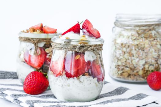 Healthy breakfast. Oatmeal Granola with greek yogurt and nuts strawberry muesli in jars on light background. Vegan, vegetarian and weight loss diet concept. Detox menu. Healthy eating food