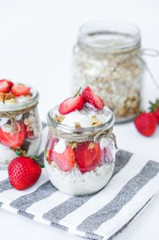 Healthy breakfast. Oatmeal Granola with greek yogurt and nuts strawberry muesli in jars on light background. Vegan, vegetarian and weight loss diet concept. Detox menu. Healthy eating food