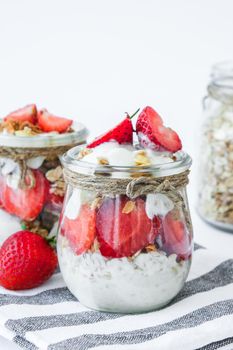 Healthy breakfast. Oatmeal Granola with greek yogurt and nuts strawberry muesli in jars on light background. Vegan, vegetarian and weight loss diet concept. Detox menu. Healthy eating food