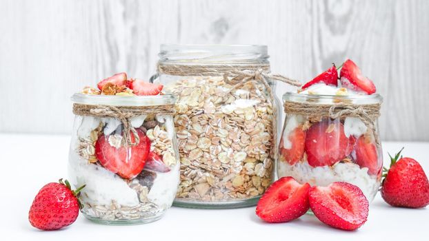 Healthy breakfast. Oatmeal Granola with greek yogurt and nuts strawberry muesli in jars on light background. Vegan, vegetarian and weight loss diet concept. Detox menu. Healthy eating food