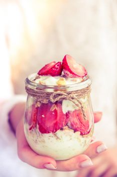 Female hands woman eating Healthy breakfast. Oatmeal Granola with greek yogurt and nuts strawberry muesli in jars on light background. Fitness. Weight loss diet concept. Detox menu. Healthy eating food